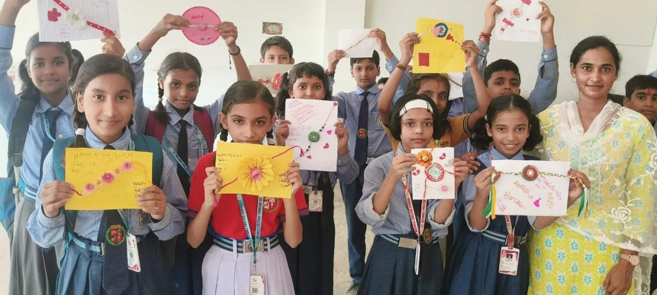 Students holding up artwork they have made, standing together in a classroom