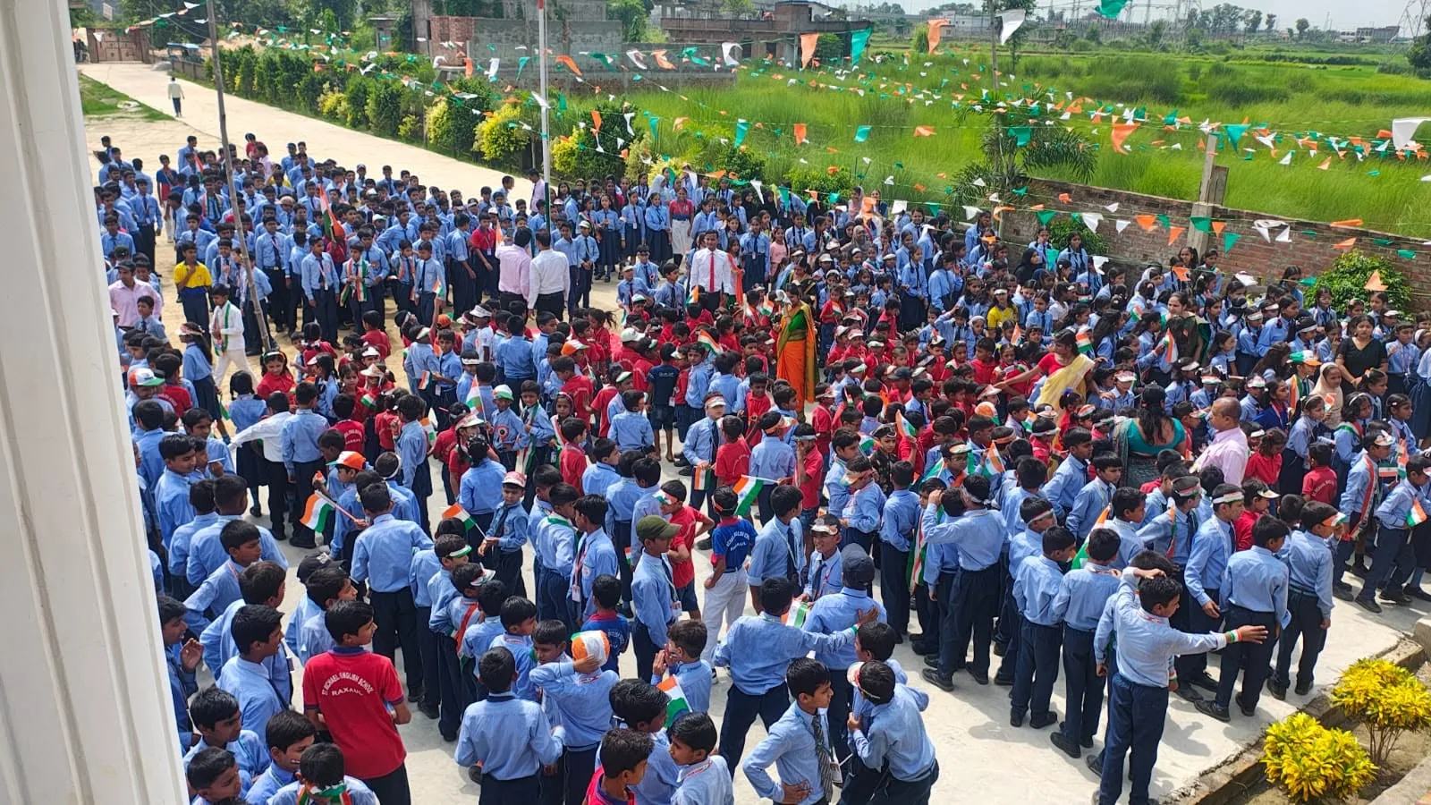 Students in blue uniform standing in rows for morning assembly in the school grounds