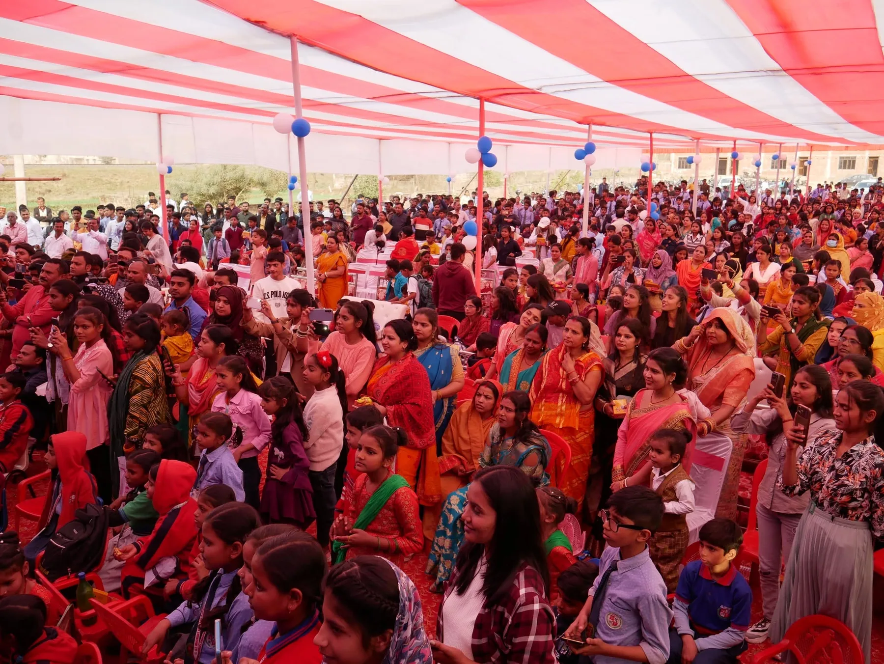 A large audience of families seated under a marquee at the school annual day