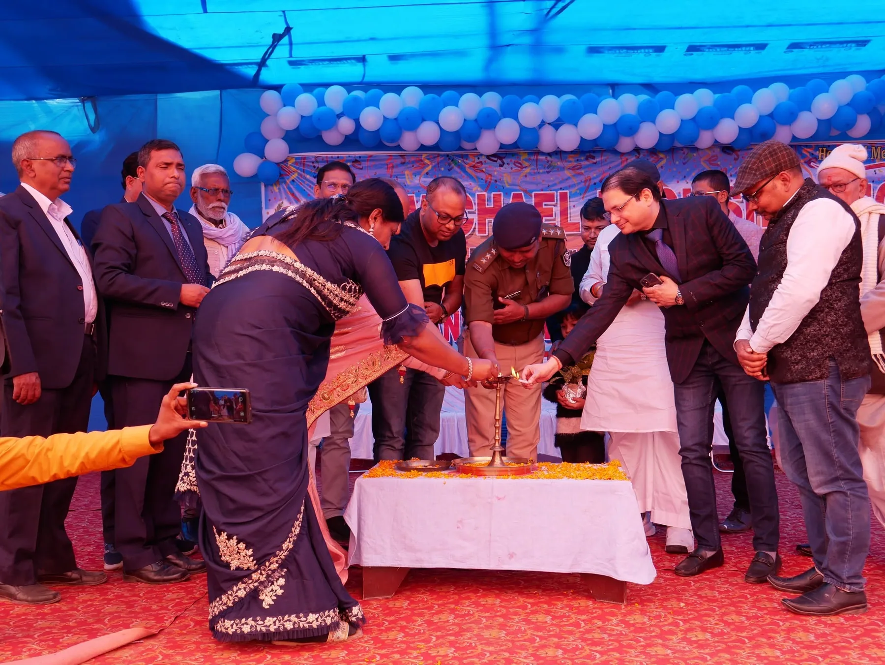 Guests gathered around a table for a cake-cutting at a school celebration